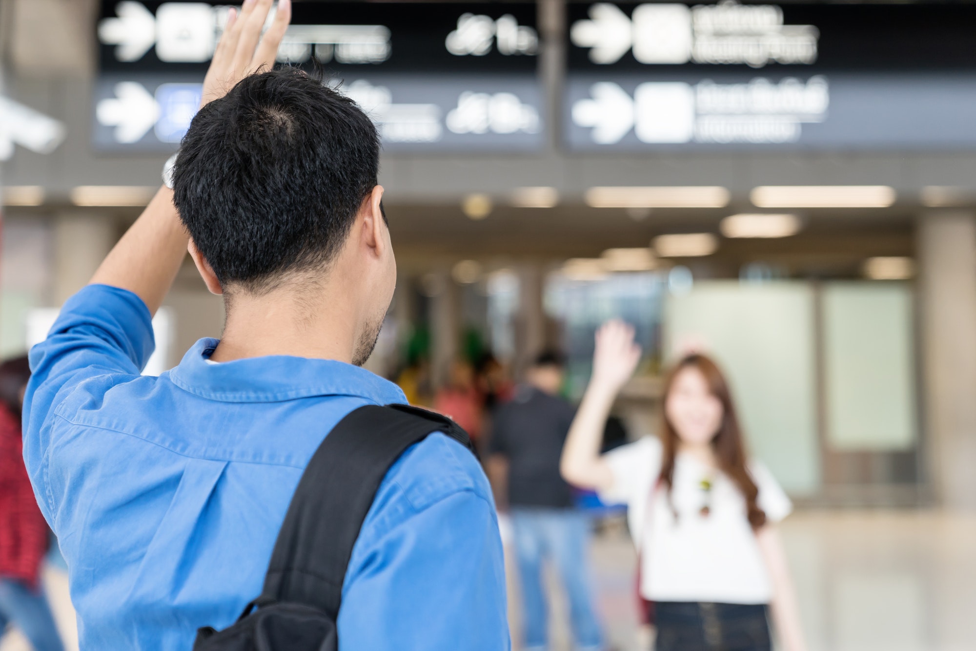 Asian couple say Hi or goodbye for abroad at airport.