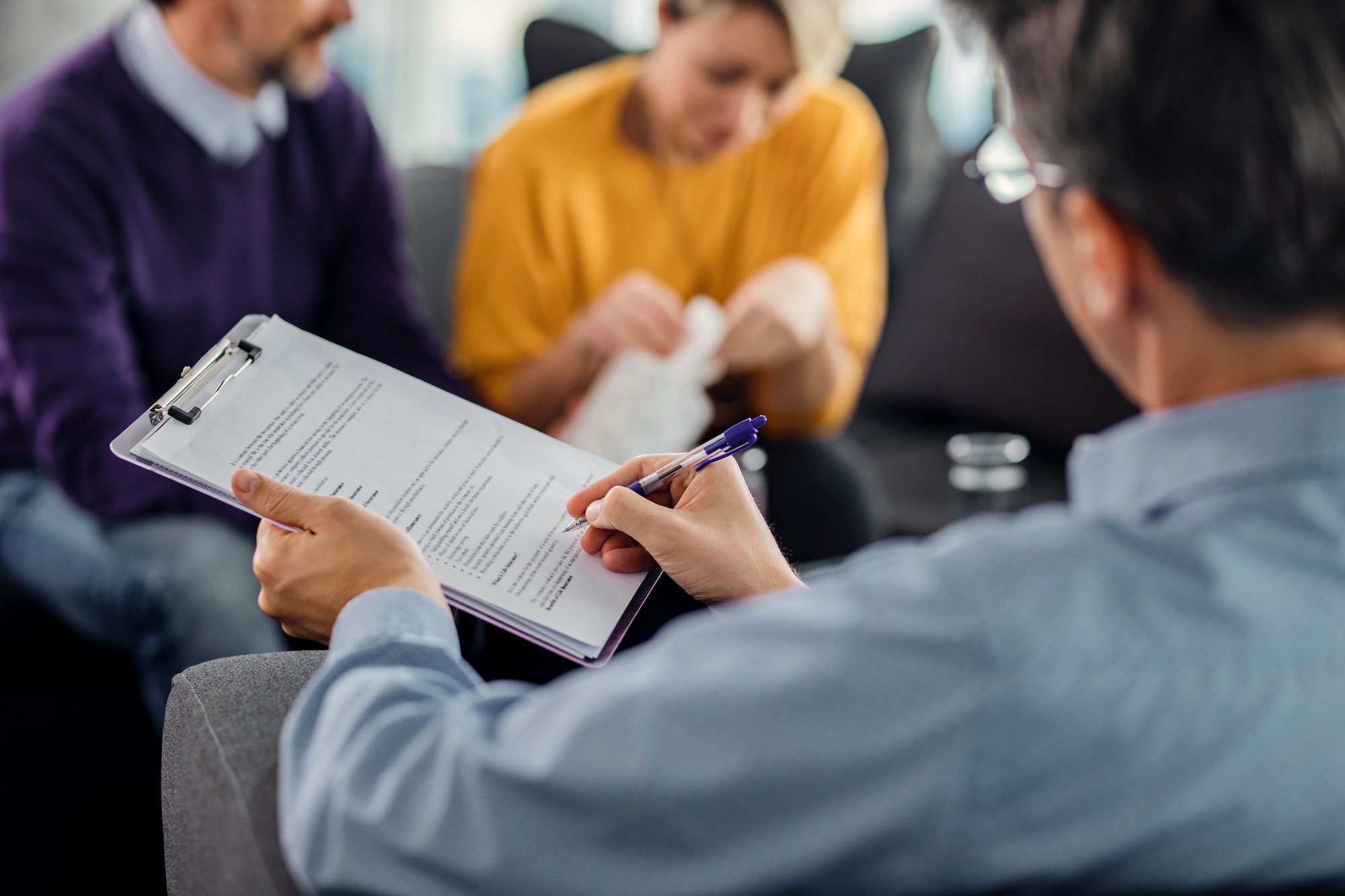 Close-up of psychotherapist writing notes during a meeting with a couple.