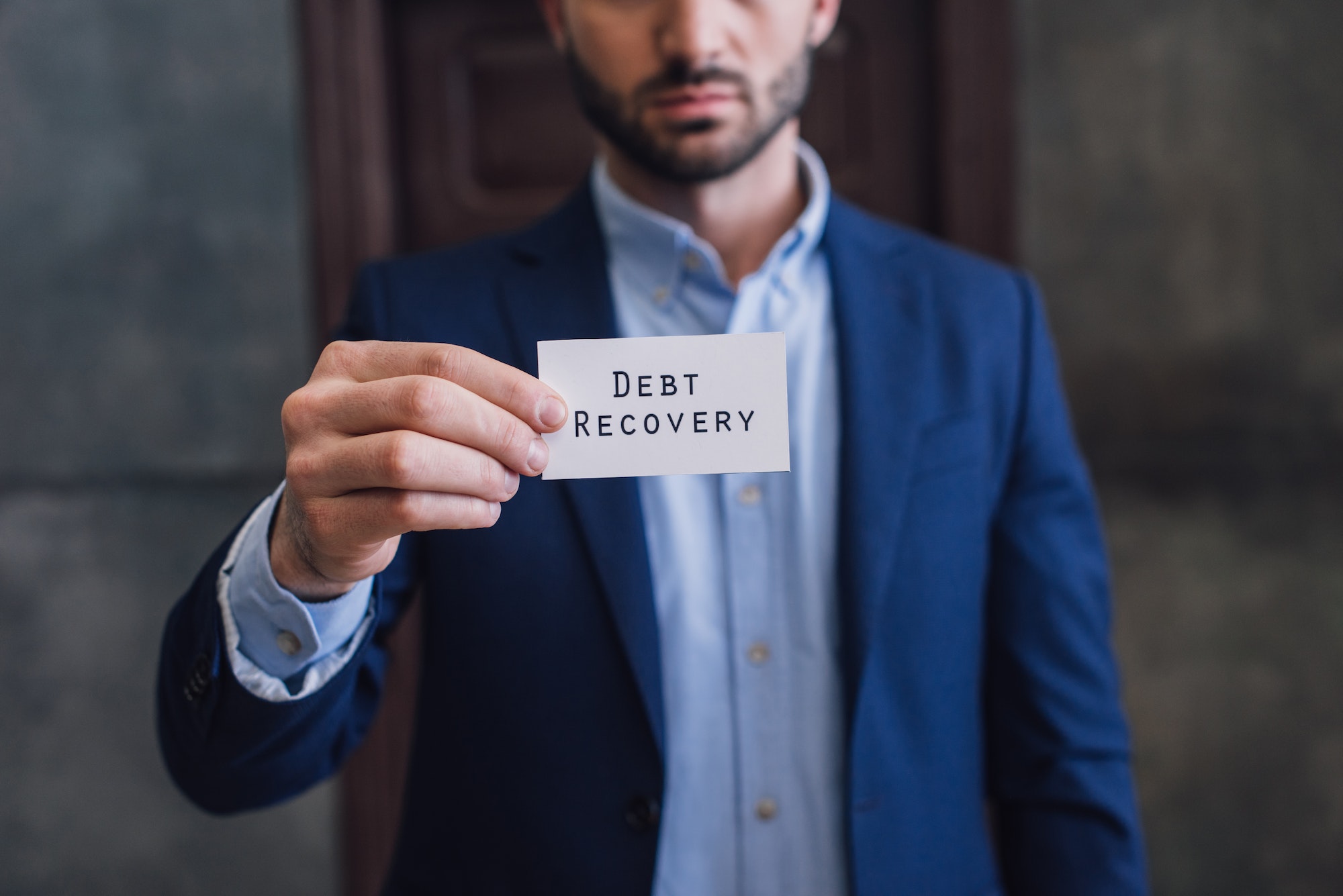 Cropped view of collector showing card with debt recovery lettering with outstretched hand