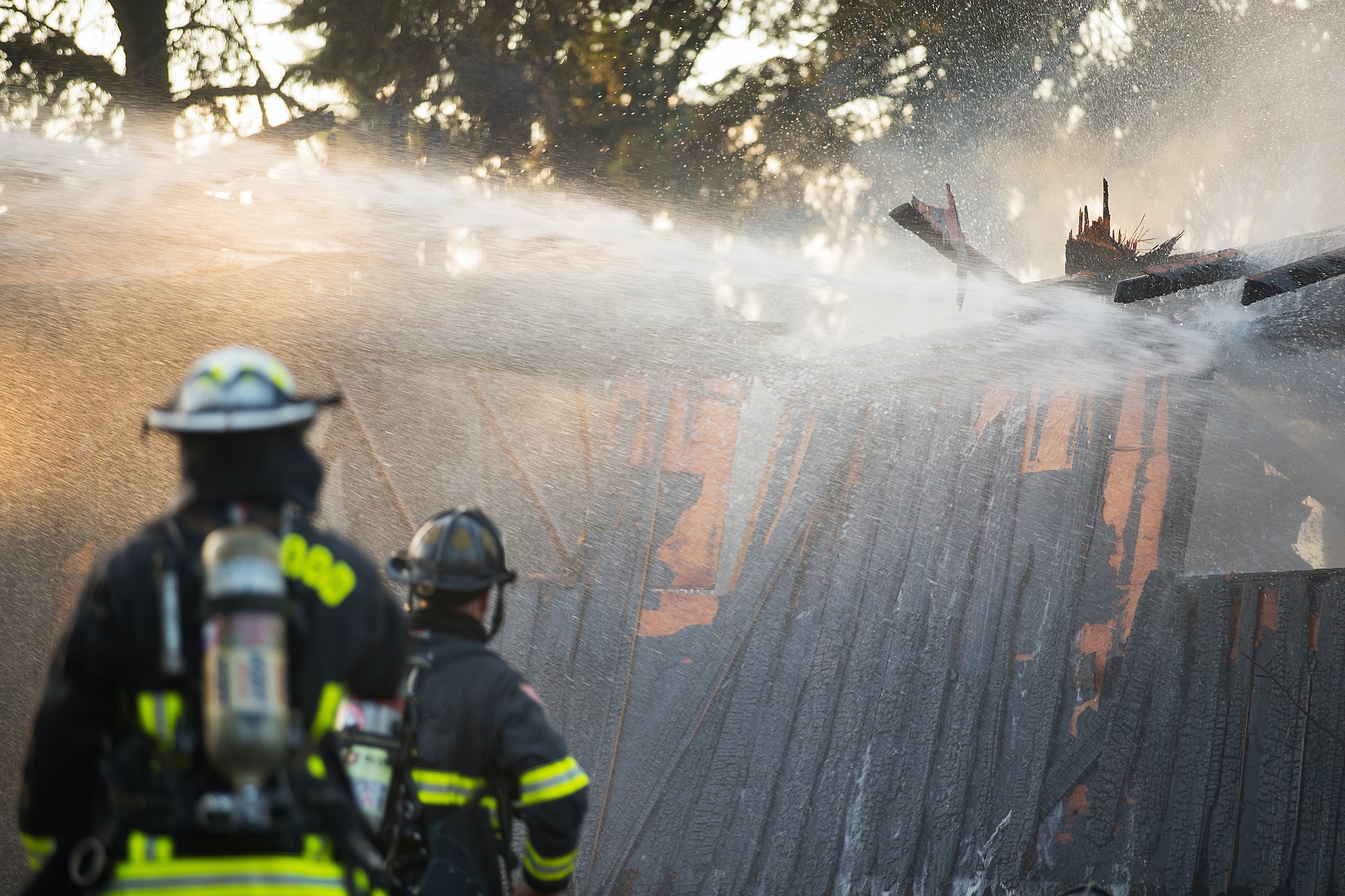 Firefighter sprays water on burning house fire