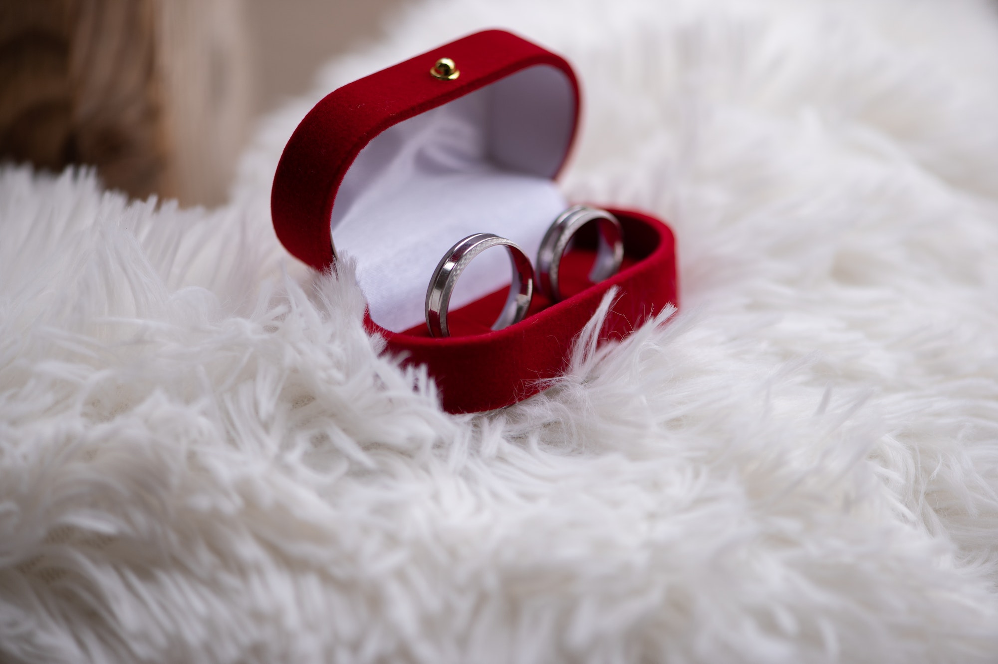 Wedding silver rings in a red box on a white pillow background