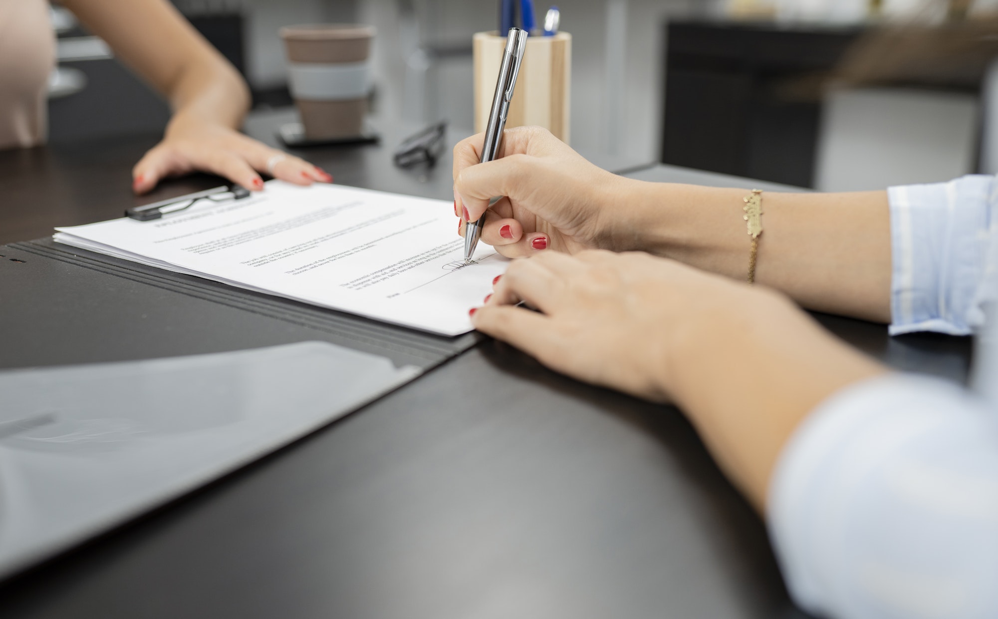 woman's hand signing employment contract